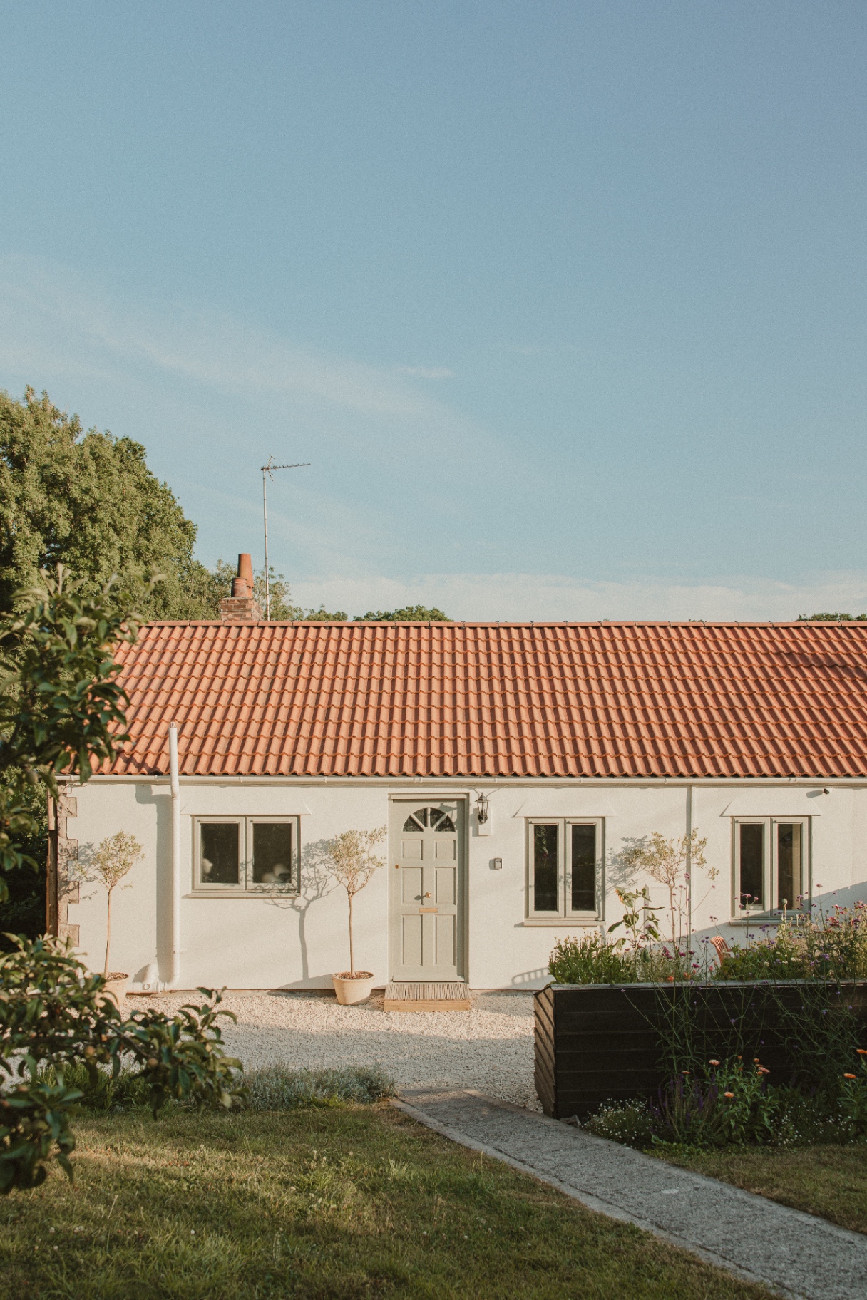 The Guesthouse - whitewashed cottage exterior with terracotta pantile roof and cottage garden