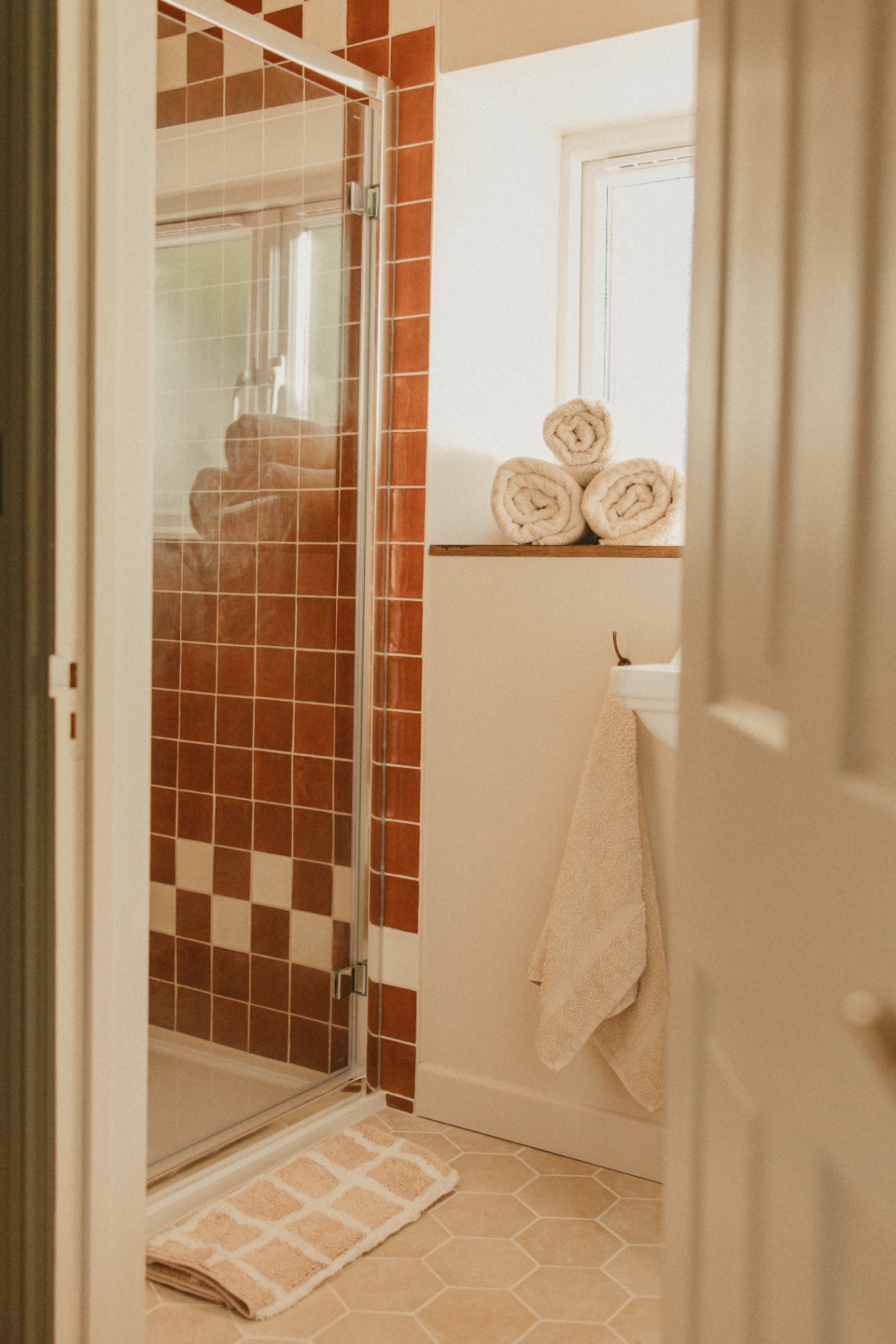 The Guesthouse - walk-in shower with terracotta tiles and rolled towels
