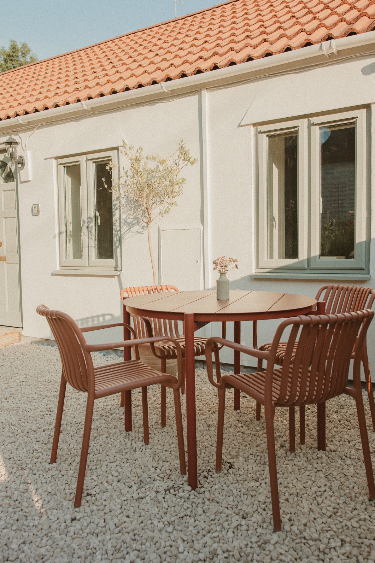 The Guesthouse - private patio with terracotta table and chairs beside the olive tree