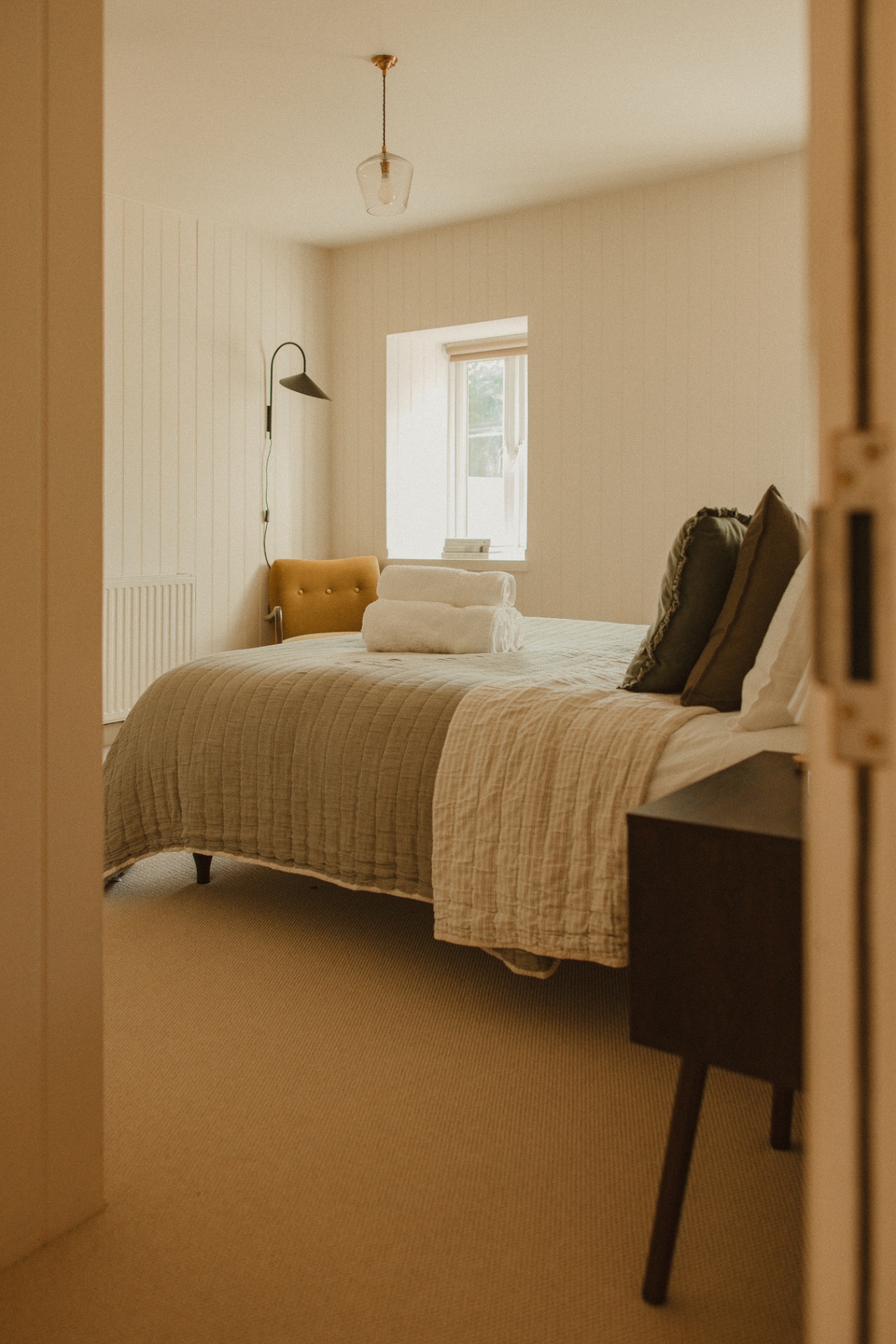 The Guesthouse - serene main bedroom with linen bedding and soft natural light