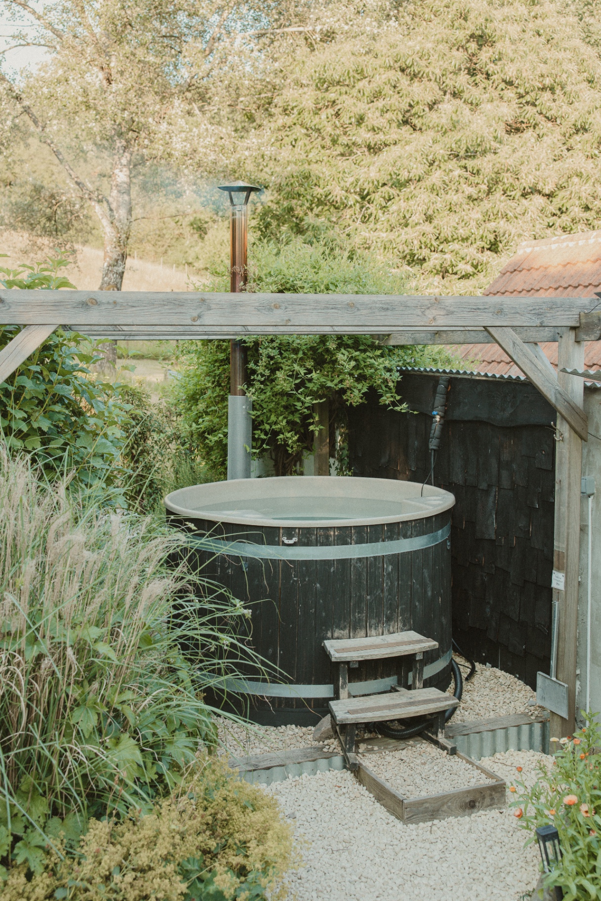 Fern - wood-fired hot tub beneath the pergola with meadow views beyond
